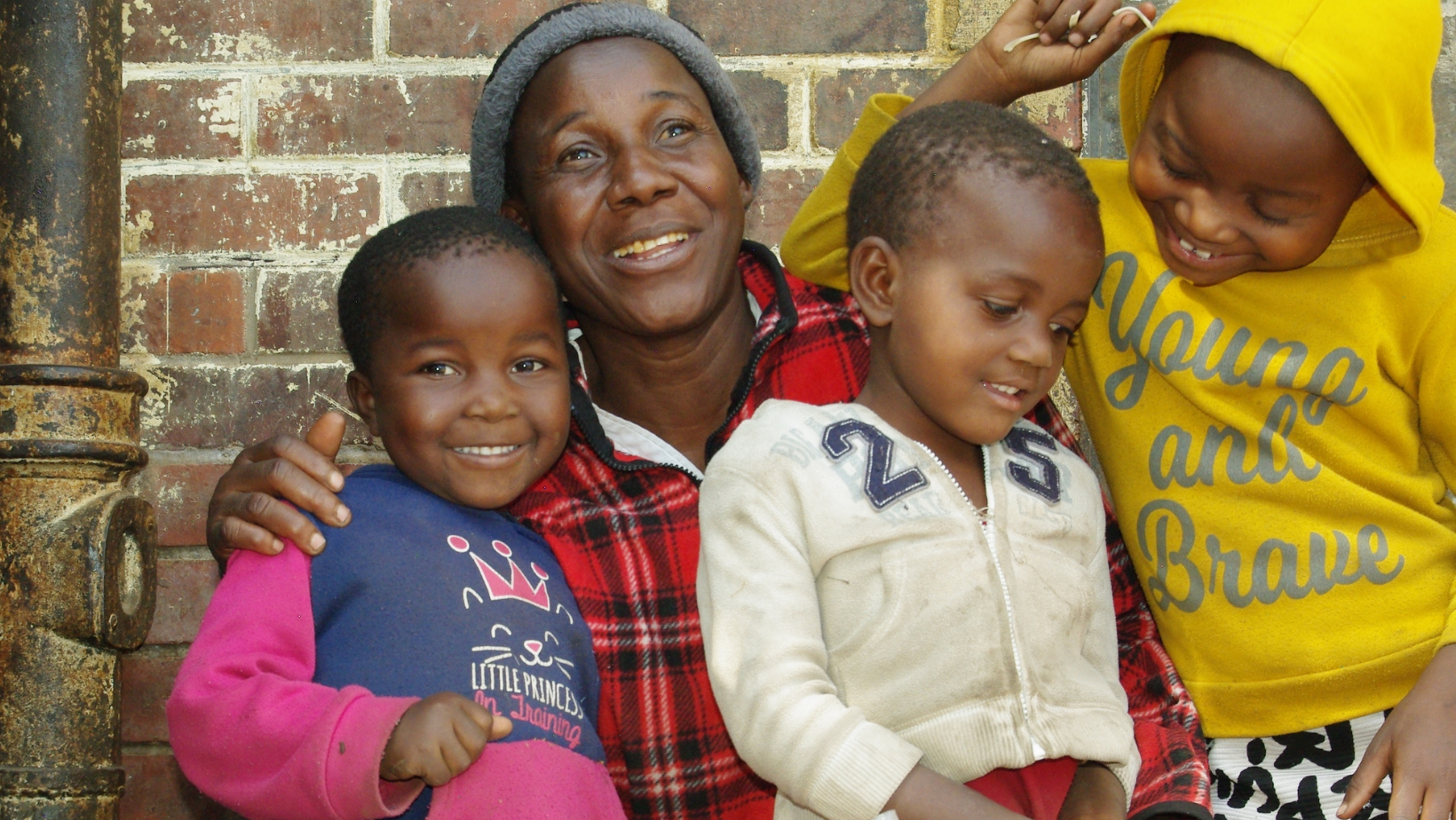 A mother puts her arms around her three young children.