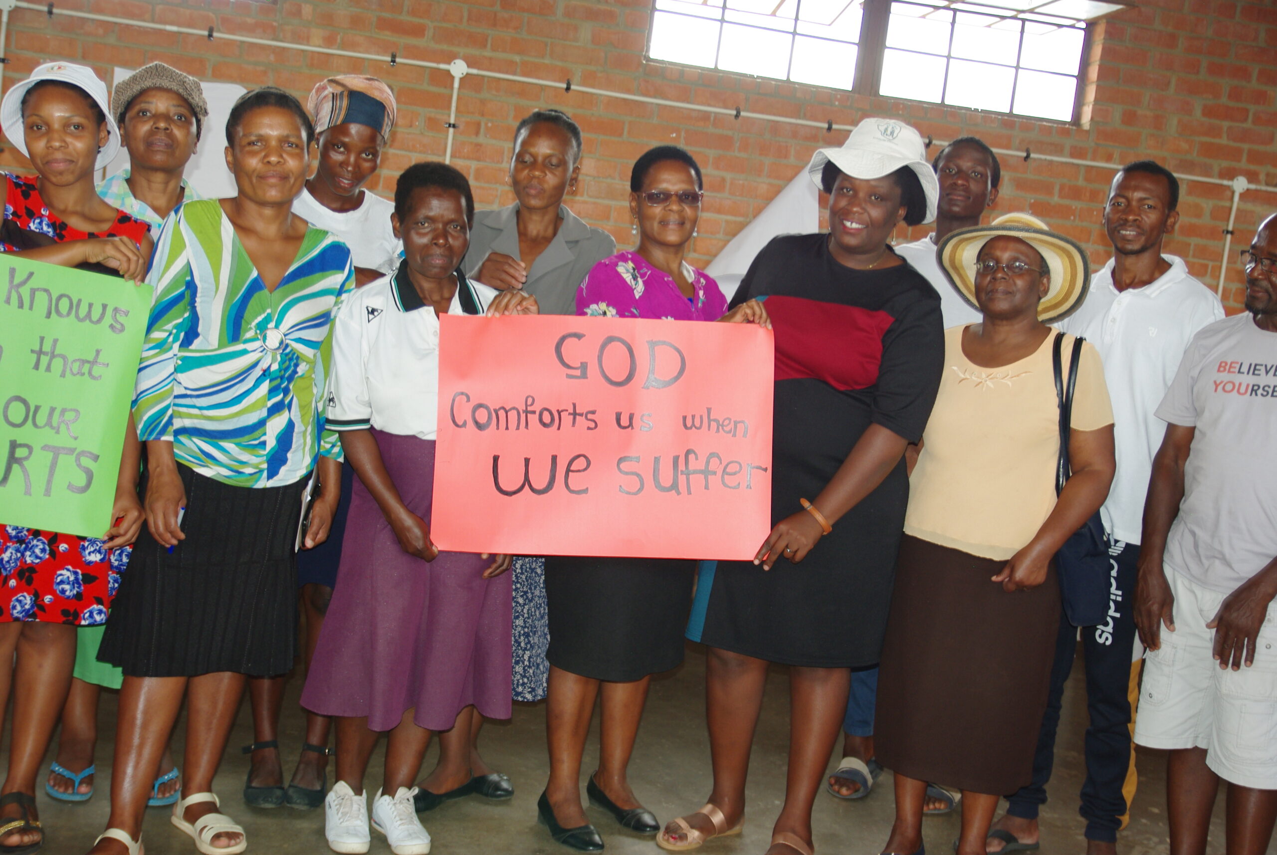 The group from BICC Trenance stands together to hold a sign reading, "God comforts us when we suffer."